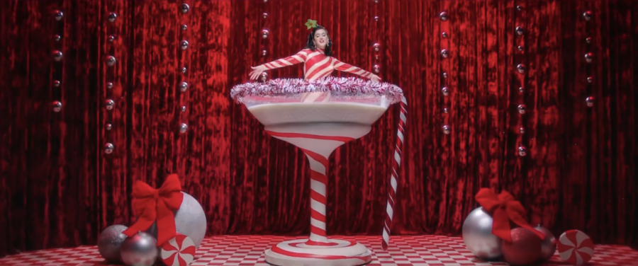 Katy Perry sitting in a life-sized glass cup of milk, decked in a candy cane bodysuit.