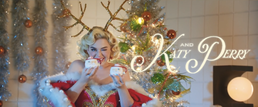 Katy Perry holding 2 Santa cups of eggnog, offering one of them to Santa.
